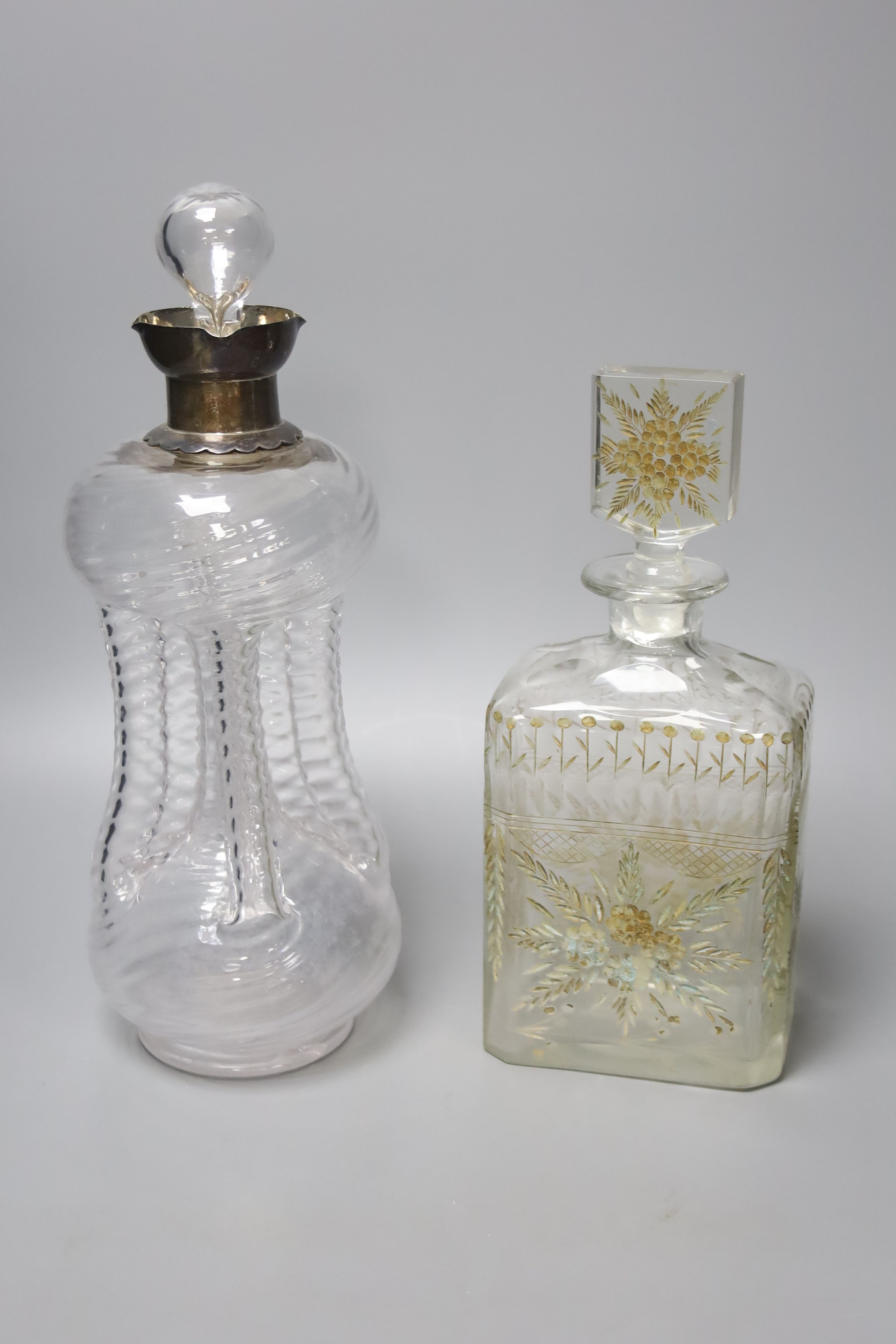 A Victorian wrythen moulded hour glass shaped decanter, with silver collar, 31cm high, togoether with a further 19th century engraved glass decanter (a.f.), 25cm high